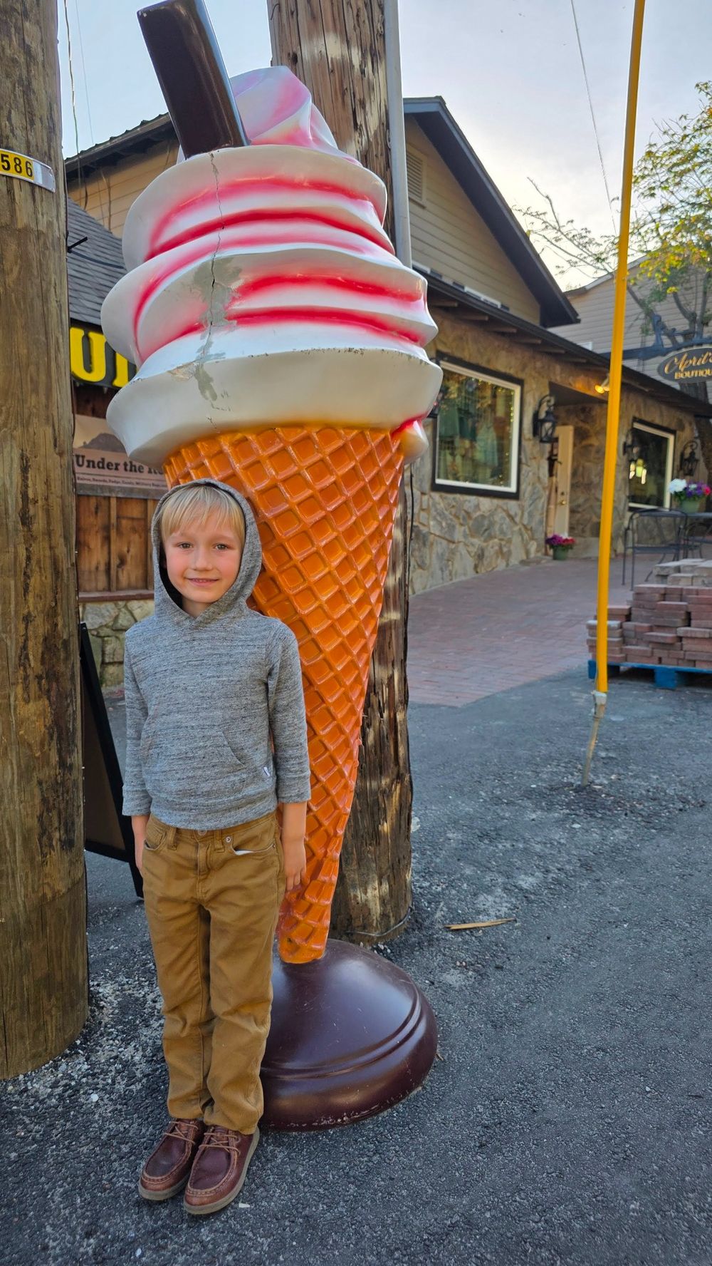 Child standing beside a large ice cream cone display near Village Scoop in Chimney Rock