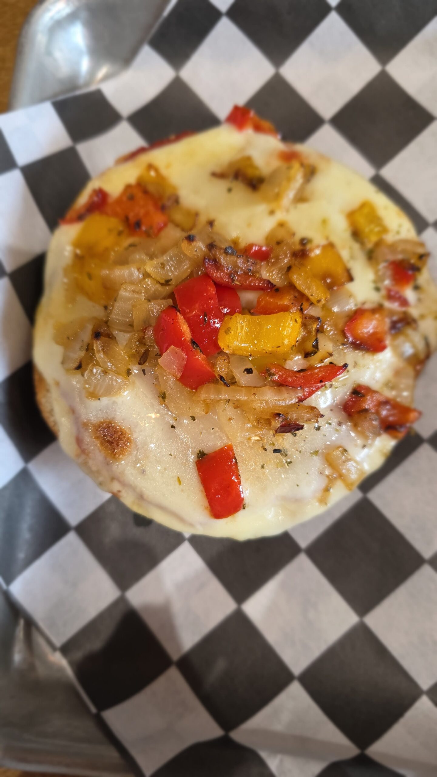 Vegetable bagel pizza with melted cheese, peppers, and onions at Goat Kick Coffee in Evans, Georgia