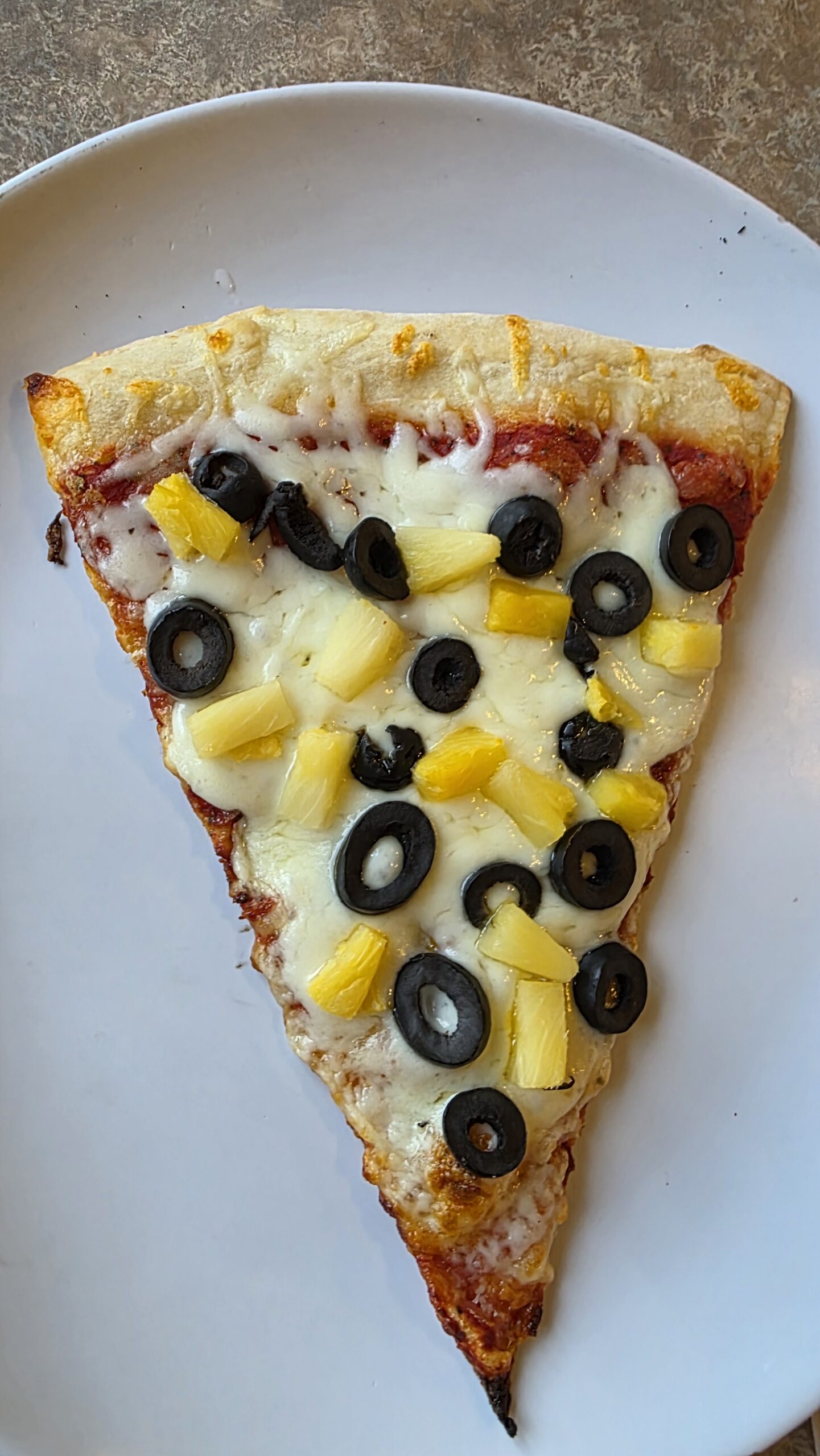 Customized pizza slice with pineapple and black olives at Ferrando’s Italian Pizzeria